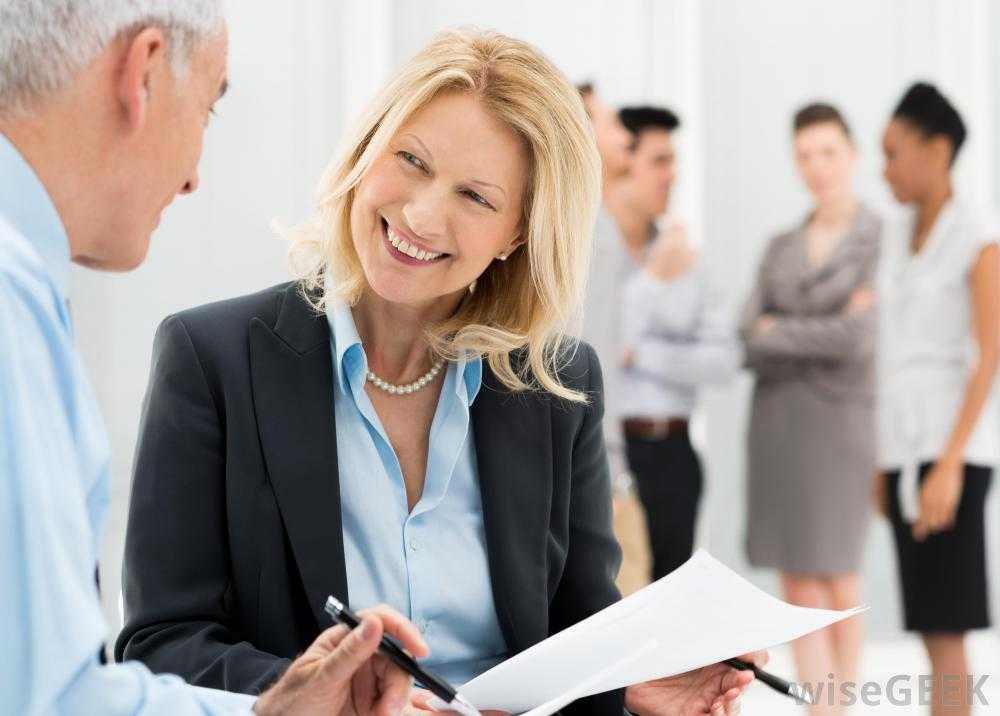 woman-in-suit-smiling-at-older-man-near-other-employees